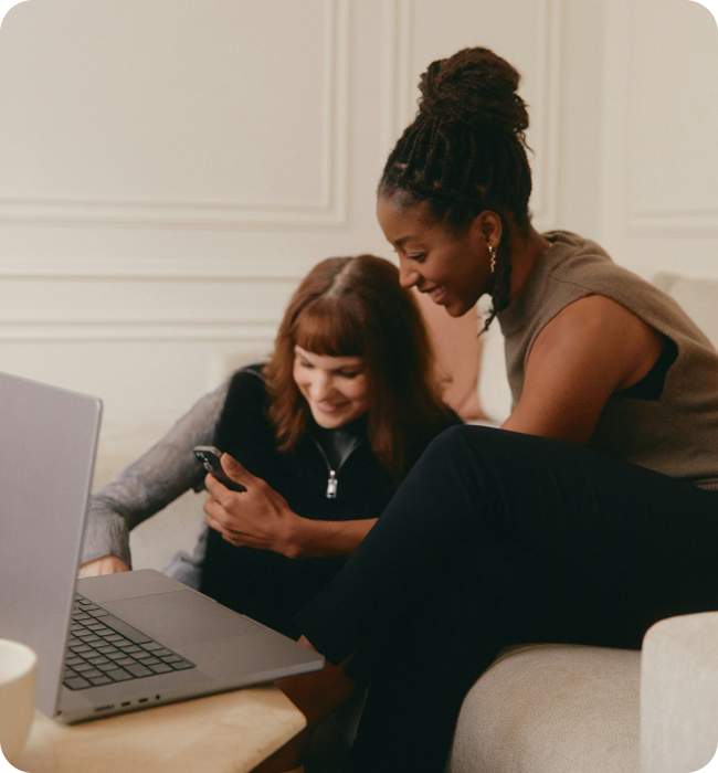 Two people looking at a laptop and phone together