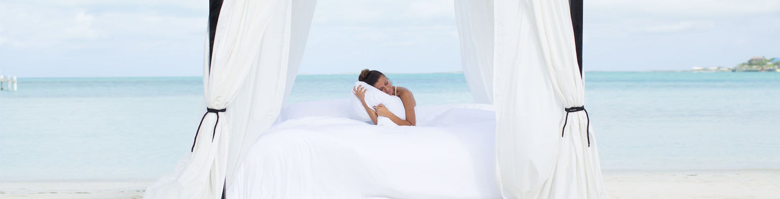 A bed using Cariloha bamboo sheets on a tropical white sand beach. 