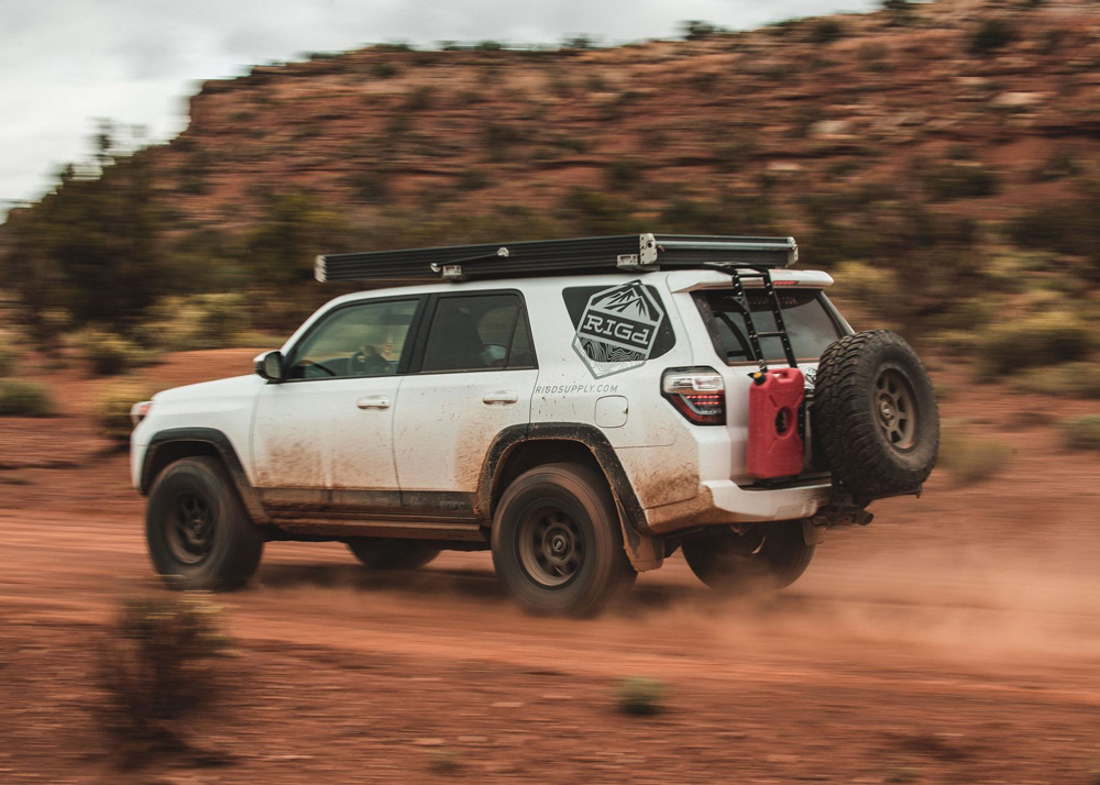 A white Toyota 4Runner zooming down a dirt road.